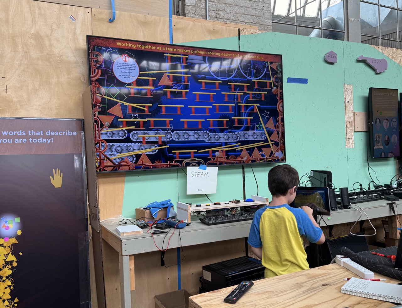 An observed play session on the museum floor — a child using a touchscreen interactive while an adult looks on